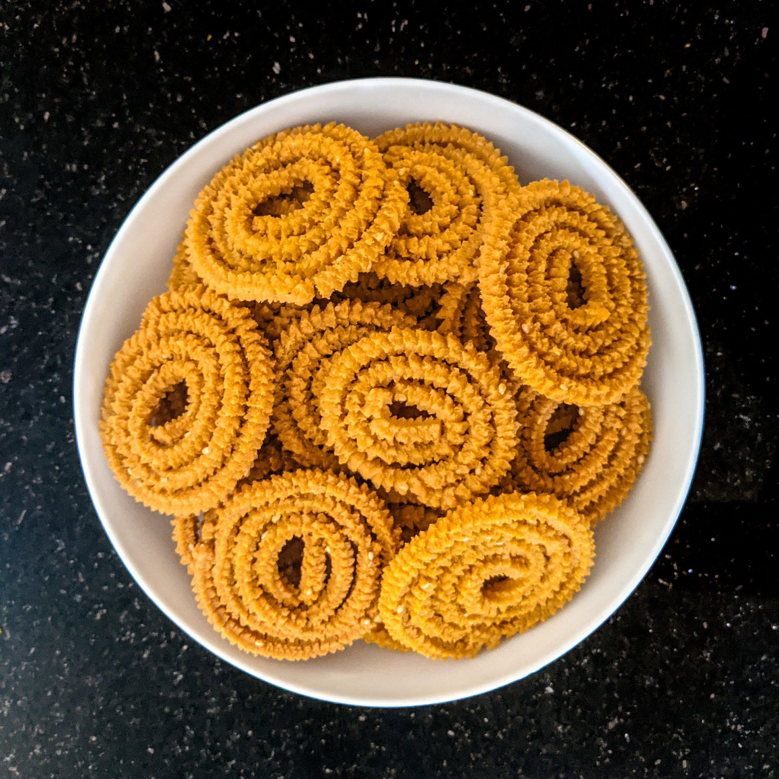 A bowl heaped with freshly fried chakli