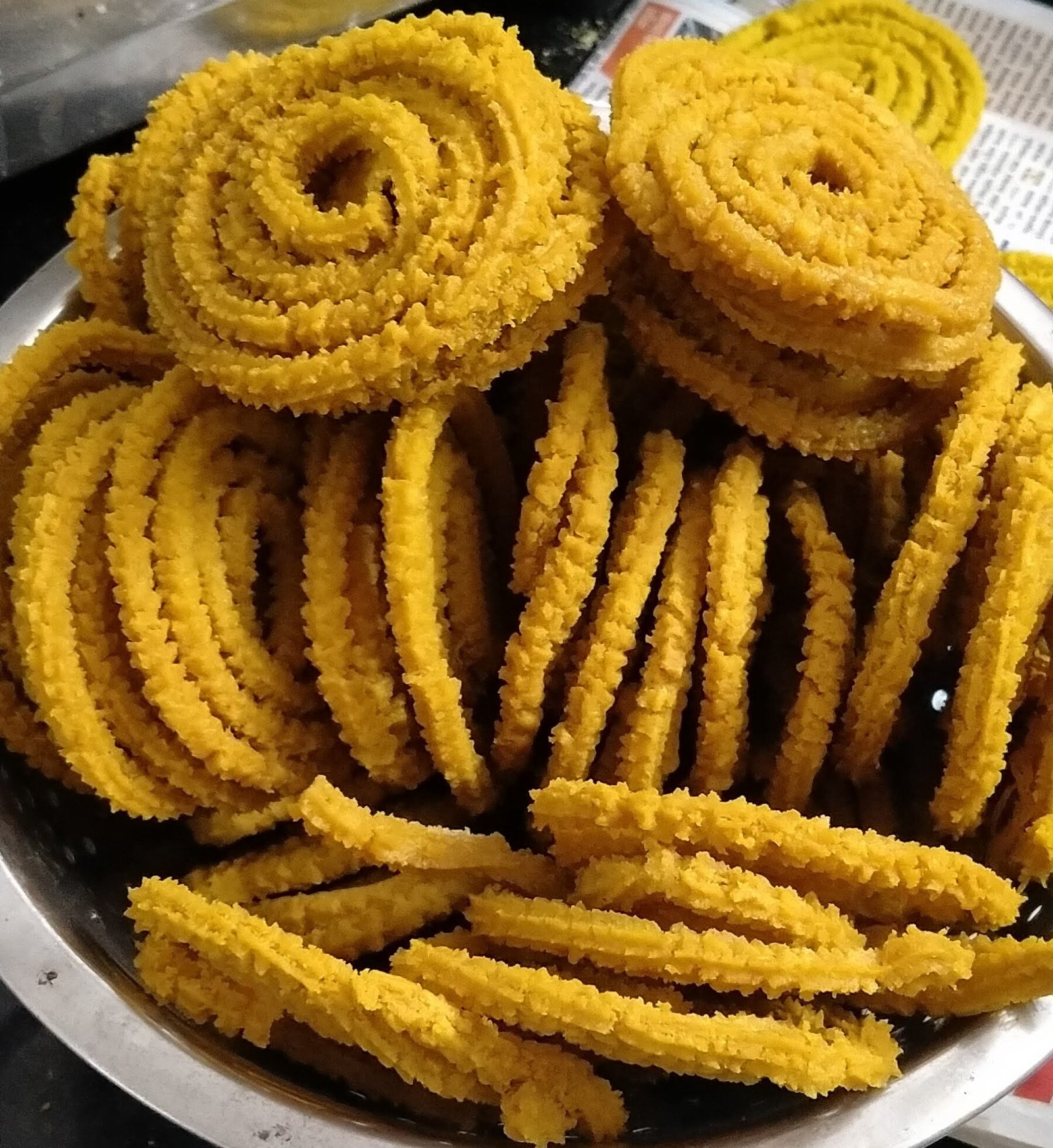 Golden spiral bhajani chakli piled in a steel plate