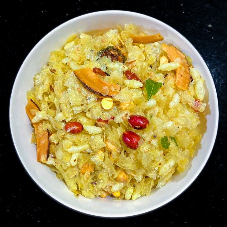 Bowl of poha chivda with peanuts, curry leaves and dalia